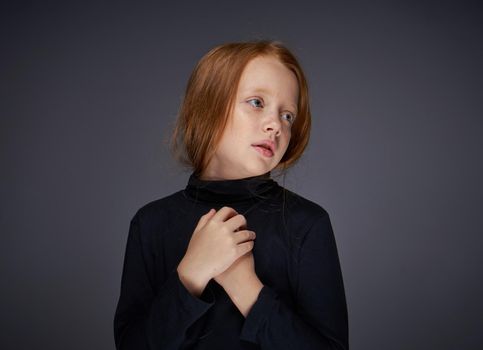 red-haired girl with freckles on her face in a black sweater posing. High quality photo
