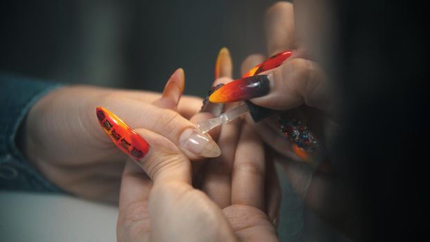 Doing manicure - applying base on the nail. Mid shot