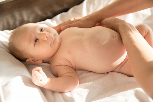A little baby lying on a bed on white sheets. Mid shot