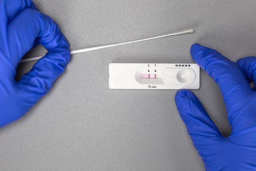 Self test kit for Covid-19 at home showing positive on gray background, Coronavirus,Covid,Health,Home test, concept with copy space and surgical gloves close up