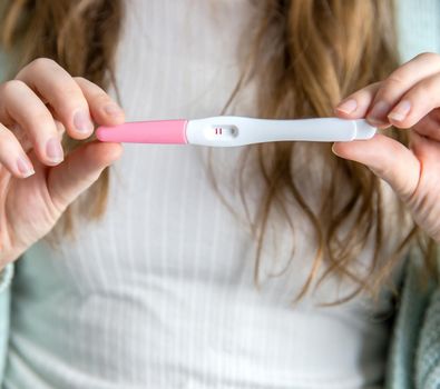 Happy young woman holding a positive pregnancy test close-up bright colors modern stylish design beautiful nature