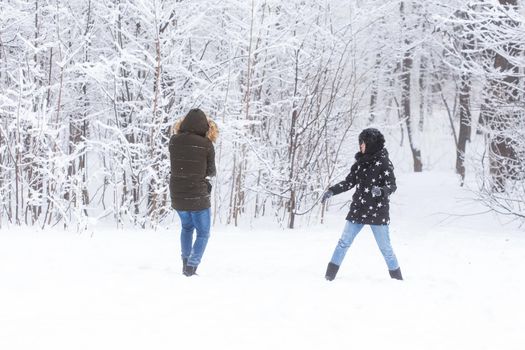 Lifestyle, season and leisure concept - Funny couple playing snowball in winter park.