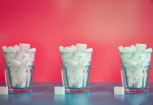 Three Glasses full with sugar cubes on pink background, sugar,unhealthy,sweets,junk food concept background retro modern design pastel colors