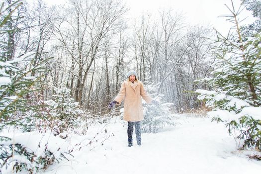 Young woman throwing snow in the air at sunny winter day, she is happy and fun