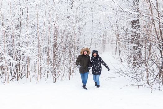 Happy couple walking through a snowy forest in winter.