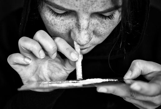 Drug Addict sniffing and snorting Cocaine,speed, Heroin or other drug with money rolled up on mirror with dark background, addiction,drugs,depressed concept portrait