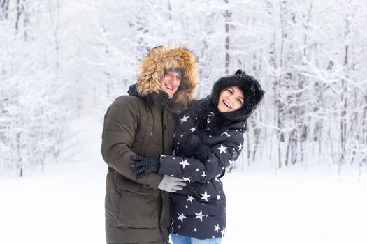 Fun, season and leisure concept - love couple plays winter wood on snow