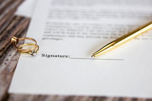 Marriage contract with two golden wedding rings and gold pen, prenuptial agreement, macro close up, sign with signanture,document,agreement concept romance