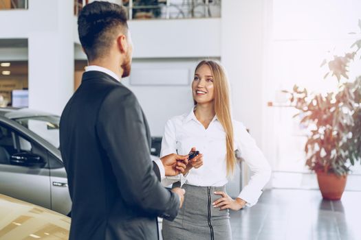 Young attractive woman buying a new car in car salon close up