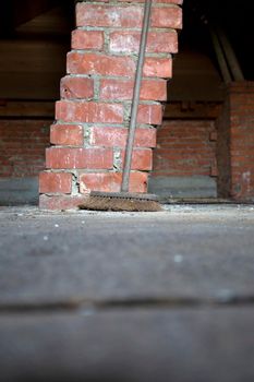 Old wooden attic with wooden beams before construction and old broom in the dark rustic and vintage style, focus on broom close up