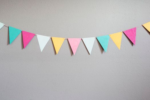 Colorful party flags over cement concrete gray wall texture background, pastel birthday colored flags with copy space Holiday concept beauty