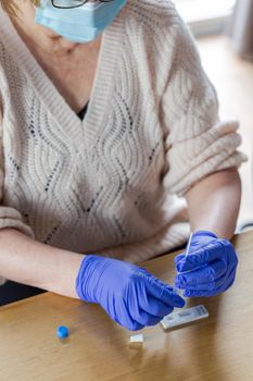 Senior woman studying and taking the self test for Covid-19, home test kit for coronavirus close-up