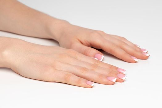 Well-groomed female hands with manicure on white background close up