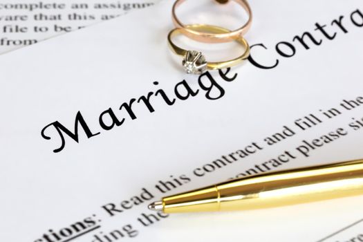 Marriage contract with two golden wedding rings and gold pen, prenuptial agreement, macro close up, sign with signanture,document,agreement concept romance