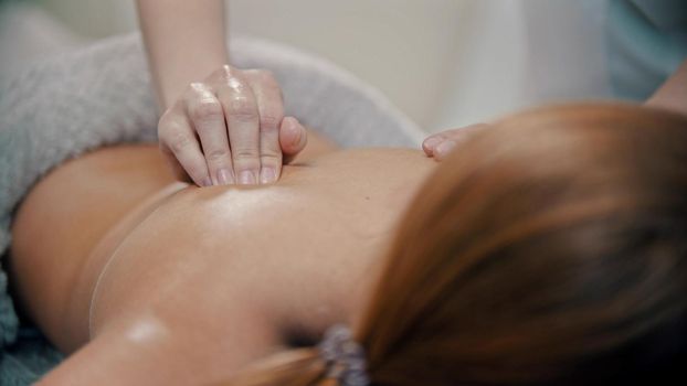 Massage procedure - massage master massaging womans back using massaging oil - indoor