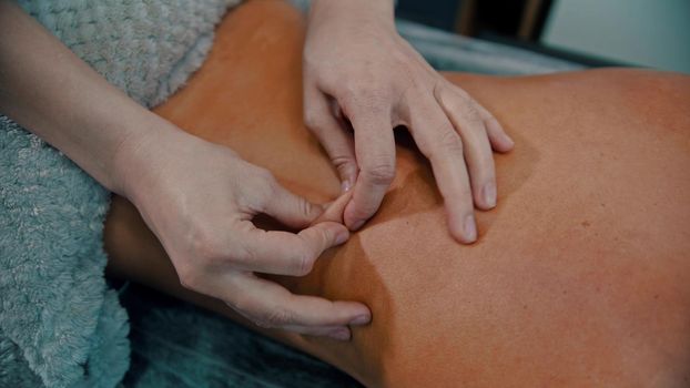 Massage treatment - massage master massaging womans back - squeeze the skin - indoor