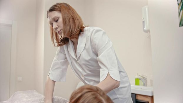Young massage master giving a massage treatment to a young woman in the cabinet - indoor