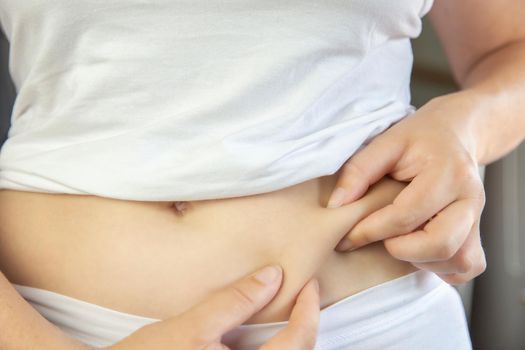 Young female wearing white underwear checking and squeeze her belly fat condition stomach closeup