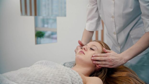 Massage - a masseuse is massaging her clients cheeks - indoor