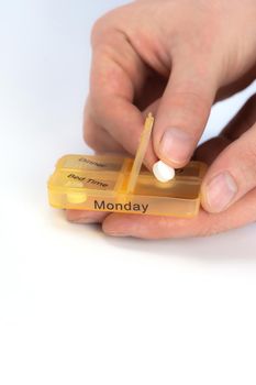 Hands of human with pill reminder box, taking medication isolated on white background, pill organizer box for monday copy space