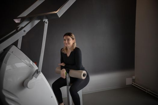 Modern gym - a young woman sitting on the strength training machine and smiling. Mid shot