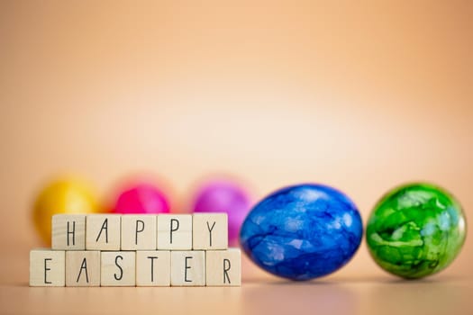 Happy Easter written with pastel colored orange background and colorful fainted Easter eggs, Bright fresh colors, Spring,Easter Holiday, greeting card concept with copy space space for text