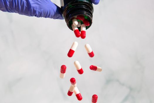 A hand grabbing pharmacy jars full of medicines, Capsules falling out Vitamines,drugs,medication. Health,business concept copy space background