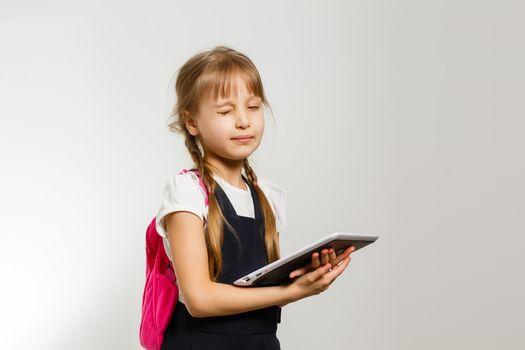 The little girl using the tablet on the white wall background