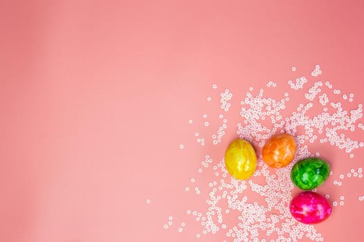 Colorful painted Easter eggs on pastel pink background with pink flowers top view, Flay lay modern design Copy space, Spring, Happy Easter Holiday concept bright fresh colors space for text