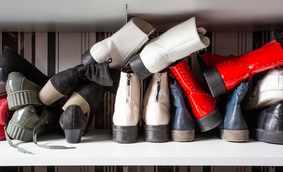 Collection of old different shoes in shoe rack for storage, messy and needs organize, wardrobe with shelfs in house interior design with copy space