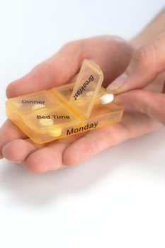 Hands of human with pill reminder box, taking medication isolated on white background, pill organizer box for monday copy space