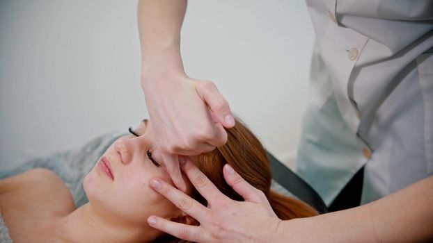 Massage - woman massage therapist massaging the face of a woman with her hands - indoor