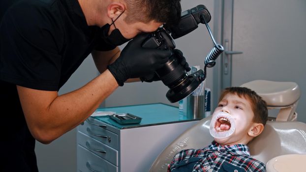 A boy having a treatment in the dentistry - the boy with opened mouth. Mid shot