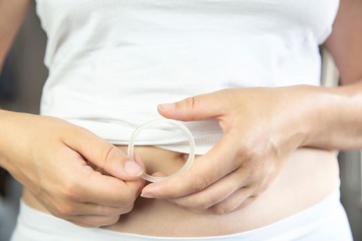 Birth control ,hormone, contraception ring in a womans hand white underwear and belly, vaginal ring for contraceptive use with copy space closeup