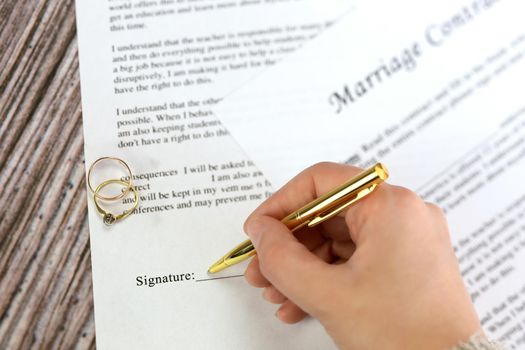 Marriage contract with two golden wedding rings and gold pen, prenuptial agreement, macro close up, sign with signanture,document,agreement concept romance