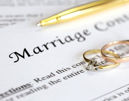 Marriage contract with two golden wedding rings and gold pen, prenuptial agreement, macro close up, sign with signanture,document,agreement concept romance