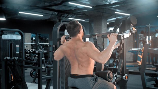 A man bodybuilder doing strength exercises in the gym. Mid shot