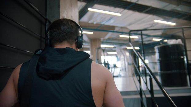 A man bodybuilder walking on stairs to the gym. Mid shot