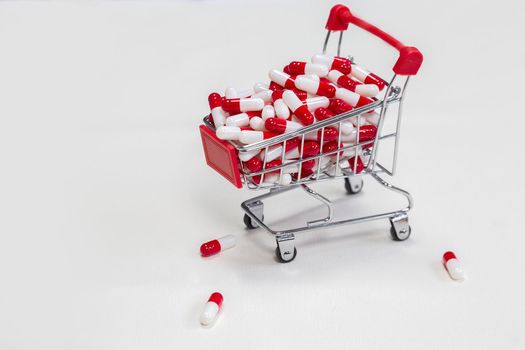 Shopping cart filled with medical capsules,pills,medication,drugs on white background top view with copy space, medicine,pharmacist and healthcare concept space for text