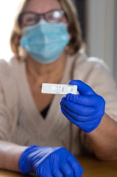 Senior woman holding a positive coronavirus self test at home, COVID-19 virus disease test,Coronavirus crisis,global pandemic outbreak,self test kit close up