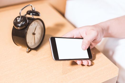 Man lying in bed turning off an alarm clock in the morning