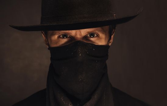 Portrait of young handsome man cowboy in a black hat and scarf
