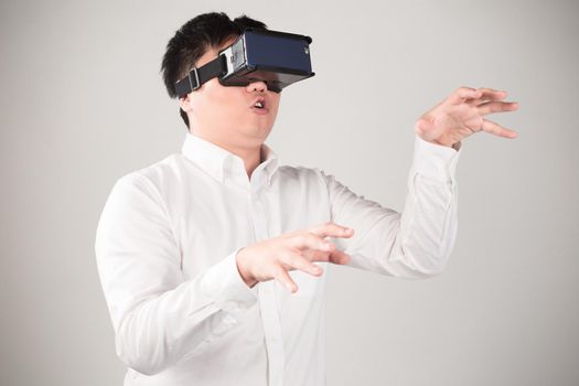 Man wearing virtual reality goggles watching movies or playing video games. He is isolated on a white background. The vr headset design is generic and no logos.