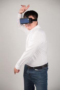 Man wearing virtual reality goggles watching movies or playing video games. He is isolated on a white background. The vr headset design is generic and no logos.