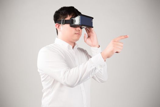 Man wearing virtual reality goggles watching movies or playing video games. He is isolated on a white background. The vr headset design is generic and no logos.