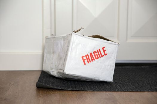 Beat up damaged delivery box with fragile sticker, broken deliverd cardboard packaging at home unhappy