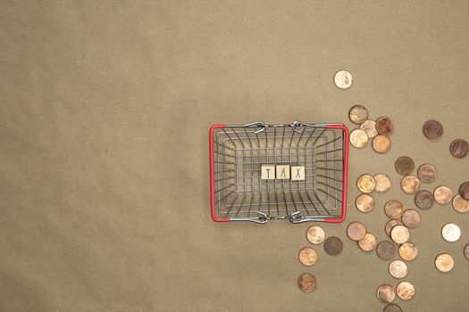 Tax written with wooden cubes top view in shopping basket with money coins and bills on the background. Business and financial concept Copy space
