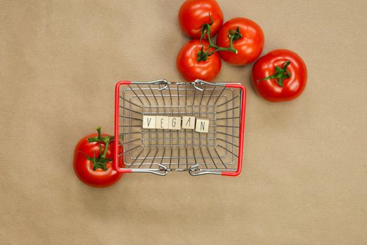 Vegan written on wooden cubes surrounded with vegetables in shoppin basket top view with craft paper background, Vegan, Healthy food, Vegetarian concept, copy space lifestyle