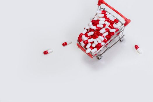 Shopping cart filled with medical capsules,pills,medication,drugs on white background top view with copy space, medicine,pharmacist and healthcare concept space for text