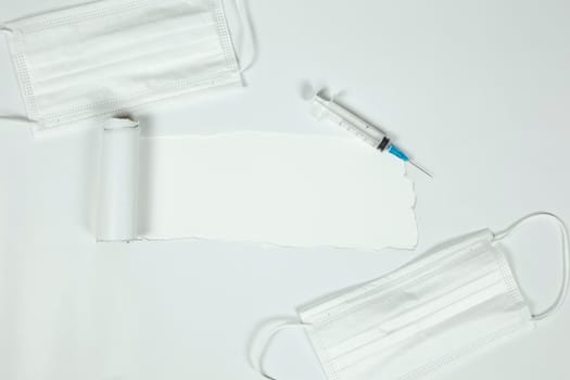 the sheet of torn paper against the white background with syringe and protective white medical mask for virus, Vaccination,health,covid-19 concept. top view, copy space space for text